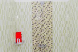 a bathroom with a shower with a red item on the wall at RedDoorz Plus @ Tuparev Cirebon 2 in Cirebon