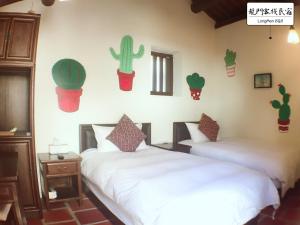 two beds in a room with cactuses on the wall at Longmen Inn Bed and Breakfast in Jinning