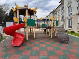 a playground with a red slide and other play equipment at Apartments Tsaritsino in Adler