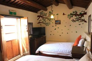 a bedroom with two beds and a tv and a tree wall at Longmen Inn Bed and Breakfast in Jinning
