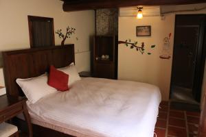 a bedroom with a white bed with a red pillow at Longmen Inn Bed and Breakfast in Jinning