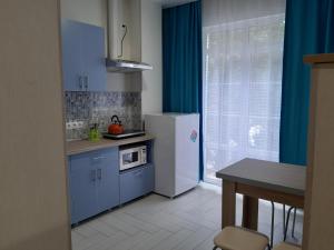 a kitchen with blue cabinets and a white refrigerator at Apartments Tsaritsino in Adler