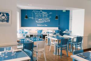 un restaurant avec des tables et des chaises bleues et blanches dans l'établissement Hotel Du Bac, à Combrit