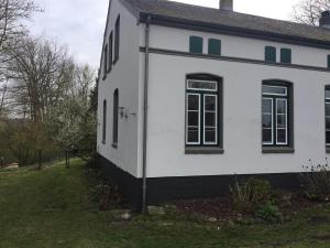 a white house with black windows and a yard at Ferien auf traumhaftem Resthof in Twedt