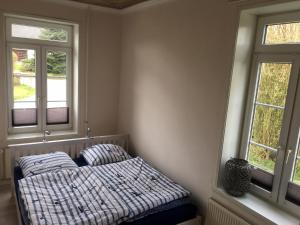 a bed sitting in a room with two windows at Ferien auf traumhaftem Resthof in Twedt