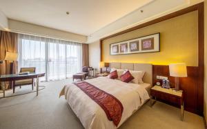 a hotel room with a large bed and a desk at Dongguan Richwood Garden Hotel in Dongguan
