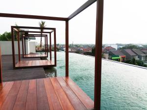 a wooden deck with a view of the water at Fabulous Studio Grand Kamala Lagoon Apartment By Travelio in Pulosirih