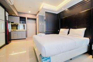 a large white bed in a room with a kitchen at Fabulous Studio Grand Kamala Lagoon Apartment By Travelio in Pulosirih