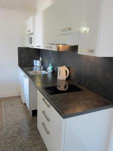 a kitchen with white cabinets and a black counter top at Résidence La Villa Léonie in Nice