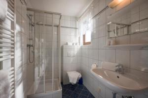 a white bathroom with a sink and a shower at Appartements Bachler in Brixen im Thale +43 photos