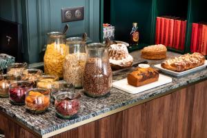 a buffet with many different types of cakes and pastries at Hotel Le Colombier in Obernai