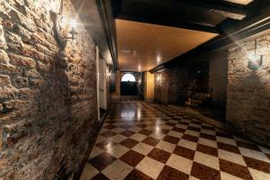 un couloir avec un mur en briques et un sol en damier dans l'établissement La Cortevecchia Venice, à Venise