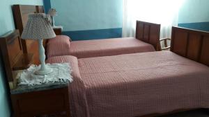 een slaapkamer met 2 bedden met roze lakens en een lamp bij Alloggio Cantalupo in Formigine