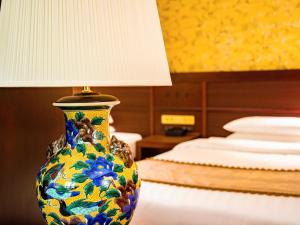a colorful vase sitting on a table next to a bed at Kanazawa Hakuchoro Hotel Sanraku -Natural Hot Spring- in Kanazawa