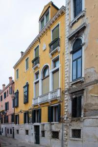 - un bâtiment jaune avec des fenêtres et des balcons dans une rue dans l'établissement La Cortevecchia Venice, à Venise
