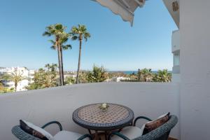 balcón con mesa, sillas y palmeras en Apartamento Marbella Real 2D, en Marbella