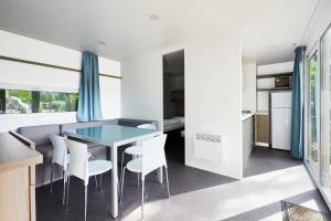 eine Küche und ein Esszimmer mit einem Glastisch und weißen Stühlen in der Unterkunft Donaupark Camping Tulln in Tulln