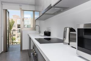 a white kitchen with a sink and a microwave at Elysia Park in Paphos