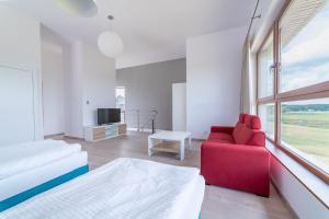 Habitación blanca con sofá rojo y TV en Apartamenty Mazury Golf & Country Club en Naterki