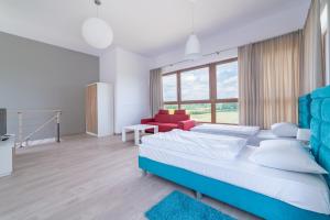 um quarto com 2 camas e um sofá vermelho em Apartamenty Mazury Golf & Country Club em Naterki