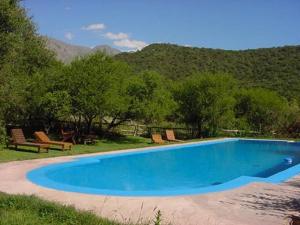 una piscina azul con sillas y montañas en el fondo en Cabañas Entrelomas en Nono