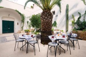 a table and chairs in a courtyard with a palm tree at Palazzo Tre Cardi in Salve