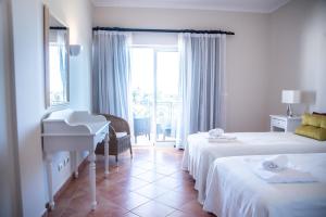 a hotel room with two beds and a piano at Colina Verde Resort in Moncarapacho