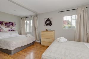 2 camas en un dormitorio con paredes y ventanas blancas en Cozy 2BD House, Minutes From FB and Stanford Univ! Home, en East Palo Alto