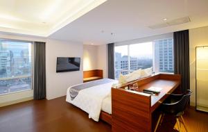 a hotel room with a bed and a desk and window at CROWN PRINCE Hotel Surabaya Managed by Midtown Indonesia in Surabaya