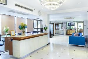 Lasalle Suites Hotel & Residence في بانكوك: لوبي مكتب مع كونتر استقبال وكراسي زرقاء
