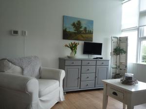 a living room with a white couch and a tv at Buitengoed Het Achterdiep in Ter Apel