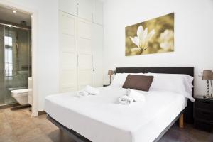 a bedroom with a large white bed and a bathroom at Stay U-nique Apartments Eixample Center in Barcelona