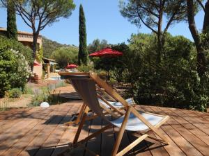 einen Stuhl und einen Regenschirm auf einer Holzterrasse in der Unterkunft Villa Thalassa Art' B&B in Le Lavandou