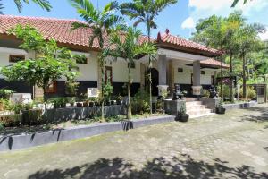 a house with palm trees in front of it at RedDoorz near Museum Gunung Merapi in Yogyakarta