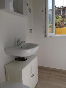 a bathroom with a white sink and a window at Casa Vacanze La Pintadera in SantʼAntìoco