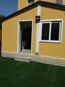 żółty dom z patio i zieloną trawą w obiekcie Casa Vacanze La Pintadera w mieście SantʼAntìoco