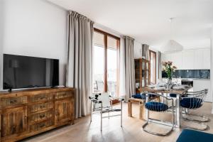a living room with a television and a table with chairs at Penthouse Uptown by LoftAffair in Krakow