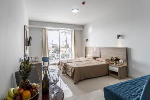 a bedroom with a bed and a table with a bowl of fruit at Bellini Hotel in Ayia Napa