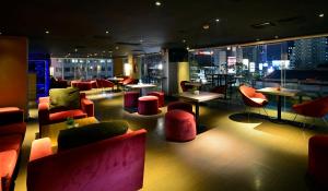 a restaurant with red chairs and tables and a city skyline at CROWN PRINCE Hotel Surabaya Managed by Midtown Indonesia in Surabaya