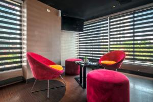 two red chairs and a table in a room with windows at CROWN PRINCE Hotel Surabaya Managed by Midtown Indonesia in Surabaya