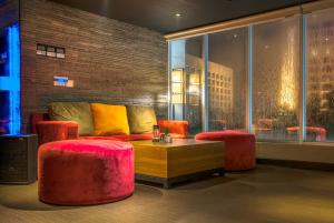 a living room with a couch and two stools at CROWN PRINCE Hotel Surabaya Managed by Midtown Indonesia in Surabaya +48 photos