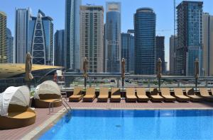 a swimming pool with chairs and a city skyline at Millennium Place Dubai Marina in Dubai