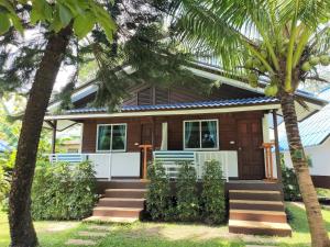 a house with palm trees in front of it at Assava Dive Resort - SHA Plus in Koh Tao