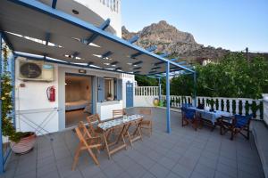 eine Terrasse mit einem Tisch und Stühlen sowie einem blauen Baldachin in der Unterkunft Panos Studios in Masouri