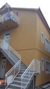 a yellow building with white stairs on the side of it at Macko, Apartmani in Tivat