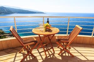 a table with a bottle of wine and two chairs on a balcony at Apartments Sunny Marina in Dobra Voda