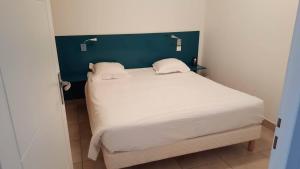 a bed with white sheets and pillows in a room at Résidence Thalacap in Cap d'Agde