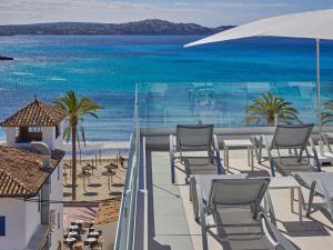 
a beach area with chairs, tables and umbrellas at Paguera Treff Boutique Hotel in Paguera
