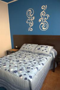 a bedroom with a bed with a blue wall with scrolls at Pensión El Parque in Avilés