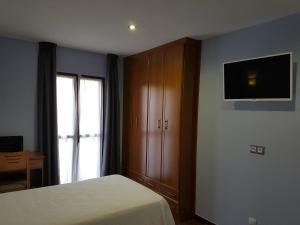 1 dormitorio con 1 cama y TV en la pared en HOSTAL CAMELOT, en Fabero
